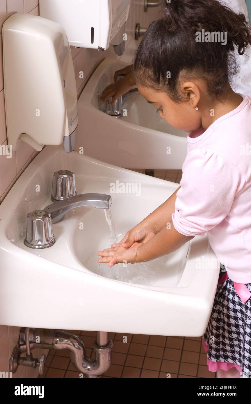 Educación Preschool aula edades 4-5 niña lavando sus propias manos en el lavabo en el baño Foto de stock