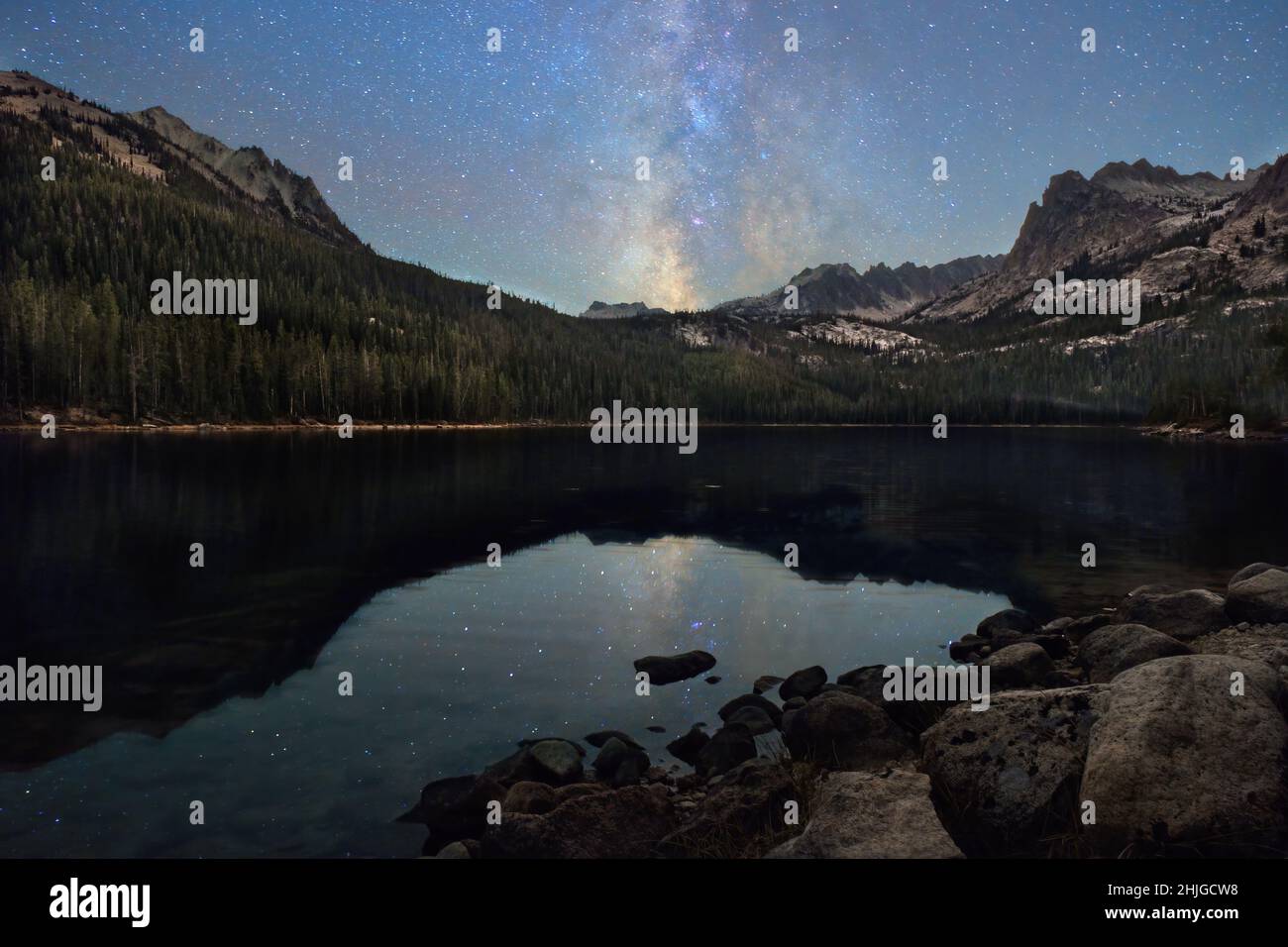 La galaxia de la Vía Láctea está suspendida sobre el Lago Infierno Roaring de Idaho, en el Bosque Nacional Sawtooth. Foto de stock
