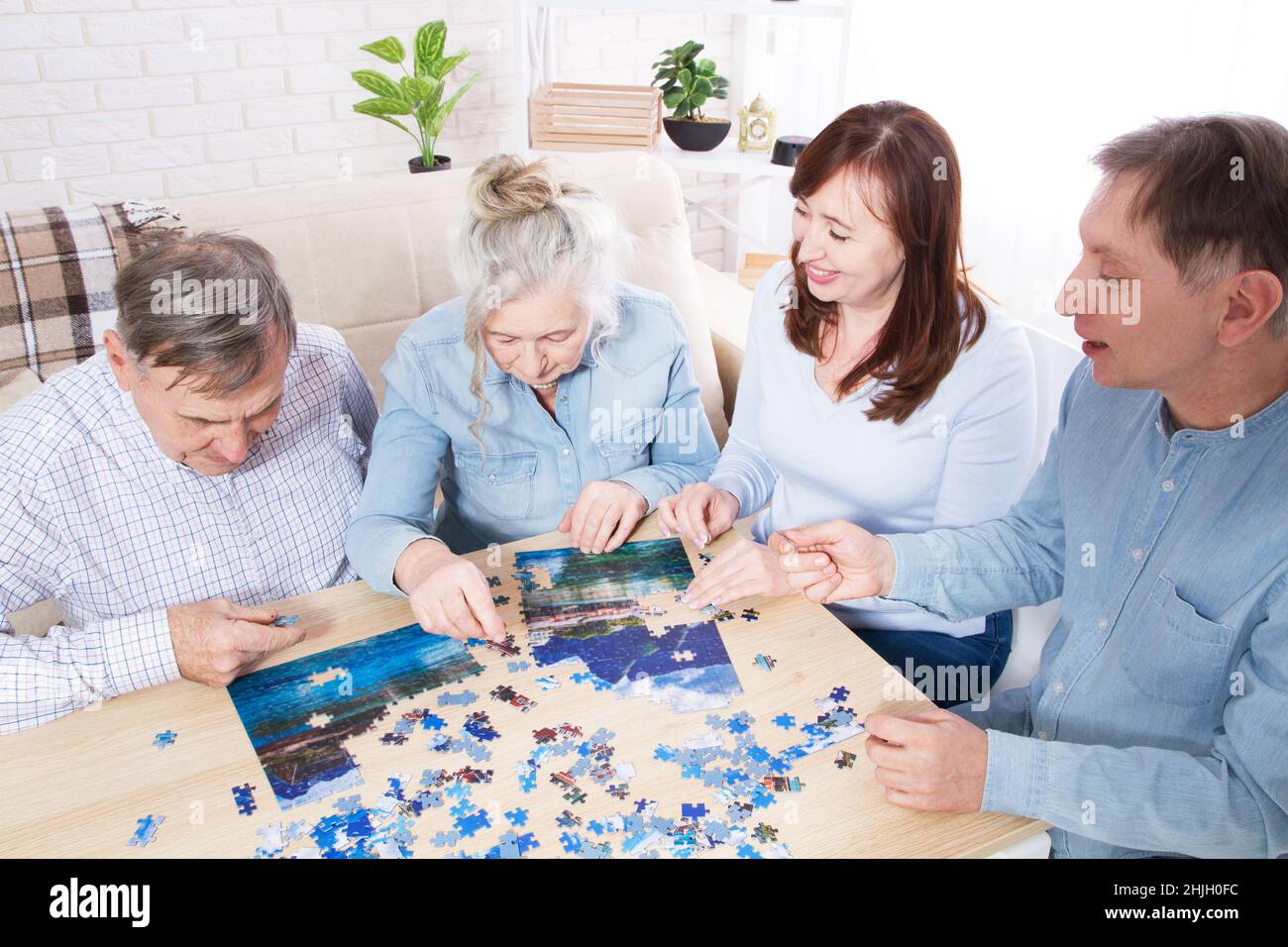 la familia juega en puzzles en casa, pareja de ancianos y pareja de mediana  edad trabajando juntos en un puzzle en casa Fotografía de stock - Alamy