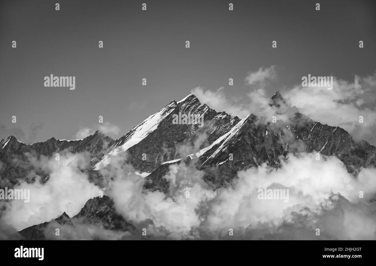 Vista panorámica del paisaje blanco y negro de los picos de montaña con nubes ventosas en un soleado día de verano, Zermatt, Suiza Foto de stock