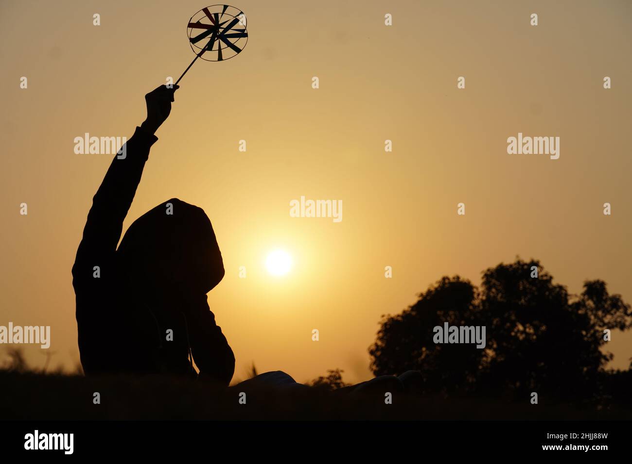 Feliz niño con un pétalo de juguete sobre un fondo de puesta de sol sobre un campo de trigo Foto de stock