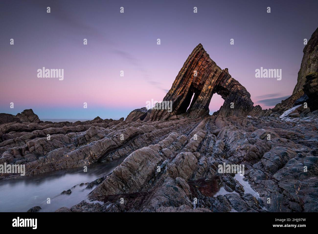 La imponente roca Blackchurch se alza en la playa de Mouthmill en Devon al atardecer Foto de stock