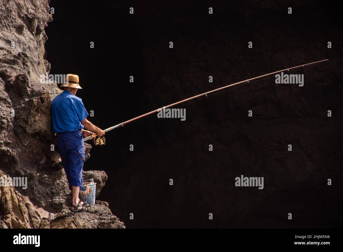 Un pescador que pesca forma la cima de un acantilado en Gran Canaria. Foto de stock