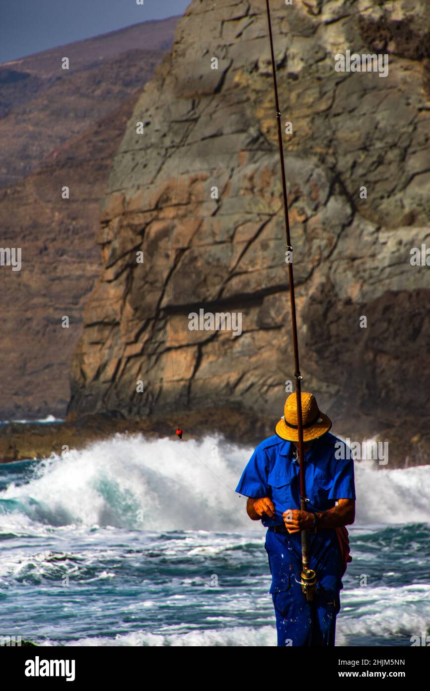 Un pescador subiendo un acantilado para ir de pesca en Gran Canaria. Foto de stock