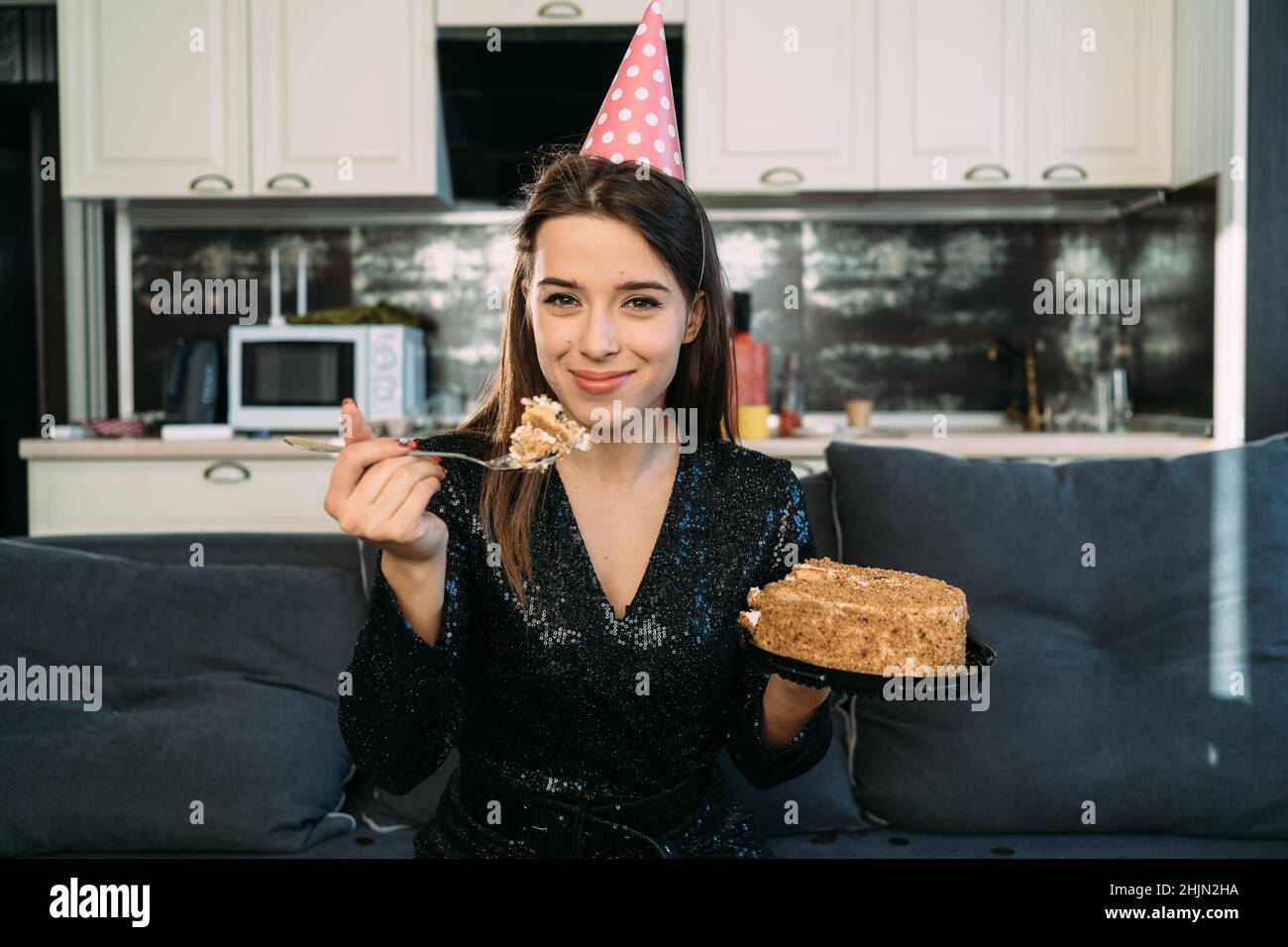 Niña comiendo pastel sentado en el sofá en casa, mirando a la cámara, la  mujer feliz tiene postre, comida chatarra y ser gordo, comida de vacaciones  Fotografía de stock - Alamy