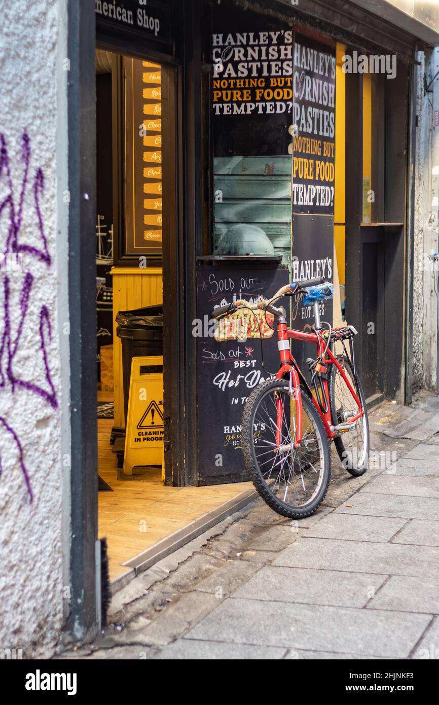 Bicicleta roja apoyada contra la pared en la zona del bar del templo a primera hora de la mañana, pubs irlandeses famosos, fotografía urbana y de calles, Dublín, Irlanda Foto de stock
