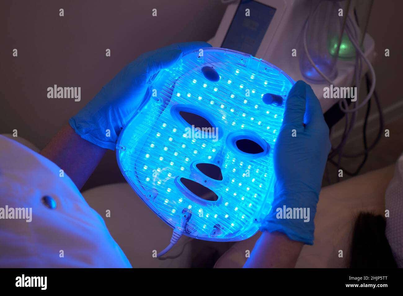 Máscara ANTI-envejecimiento con luz LED para el cuidado facial de la piel  en un spa a cámara lenta. Una mujer se acuesta en un sofá en una máscara  especial. Tecnologías modernas de