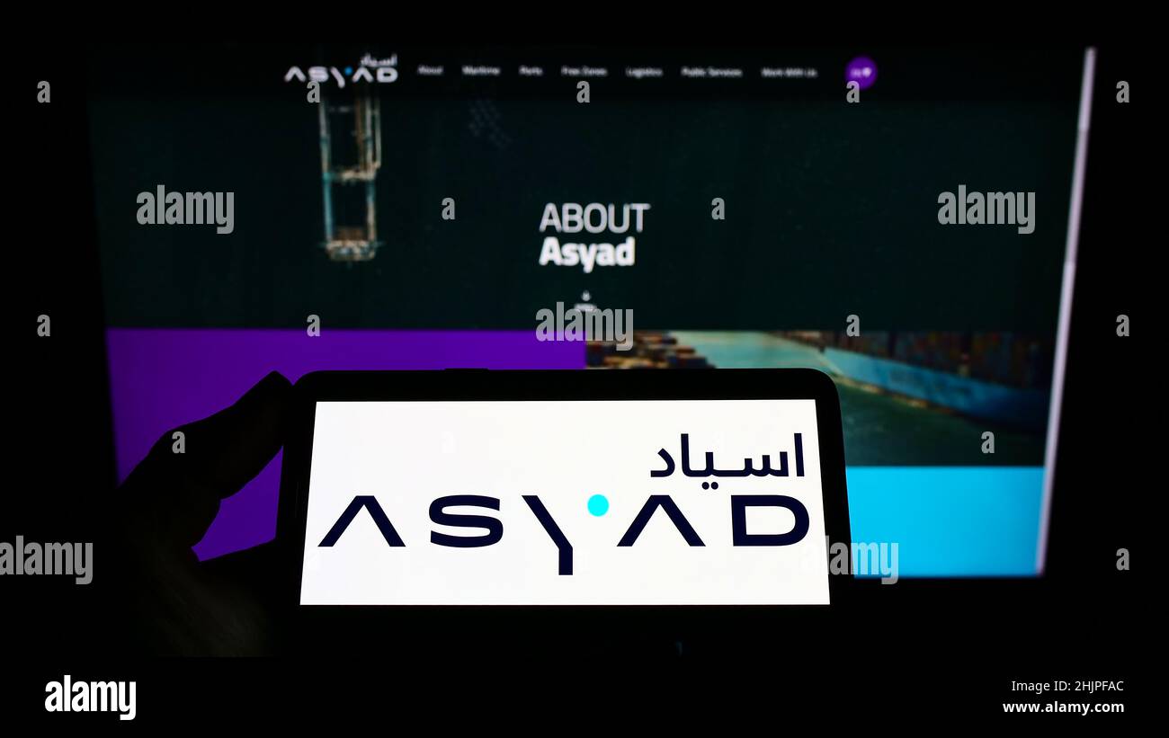 Persona que sostiene un smartphone con el logotipo de la compañía logística de Omán ASYAD Group en la pantalla frente al sitio web. Enfoque en la pantalla del teléfono. Foto de stock