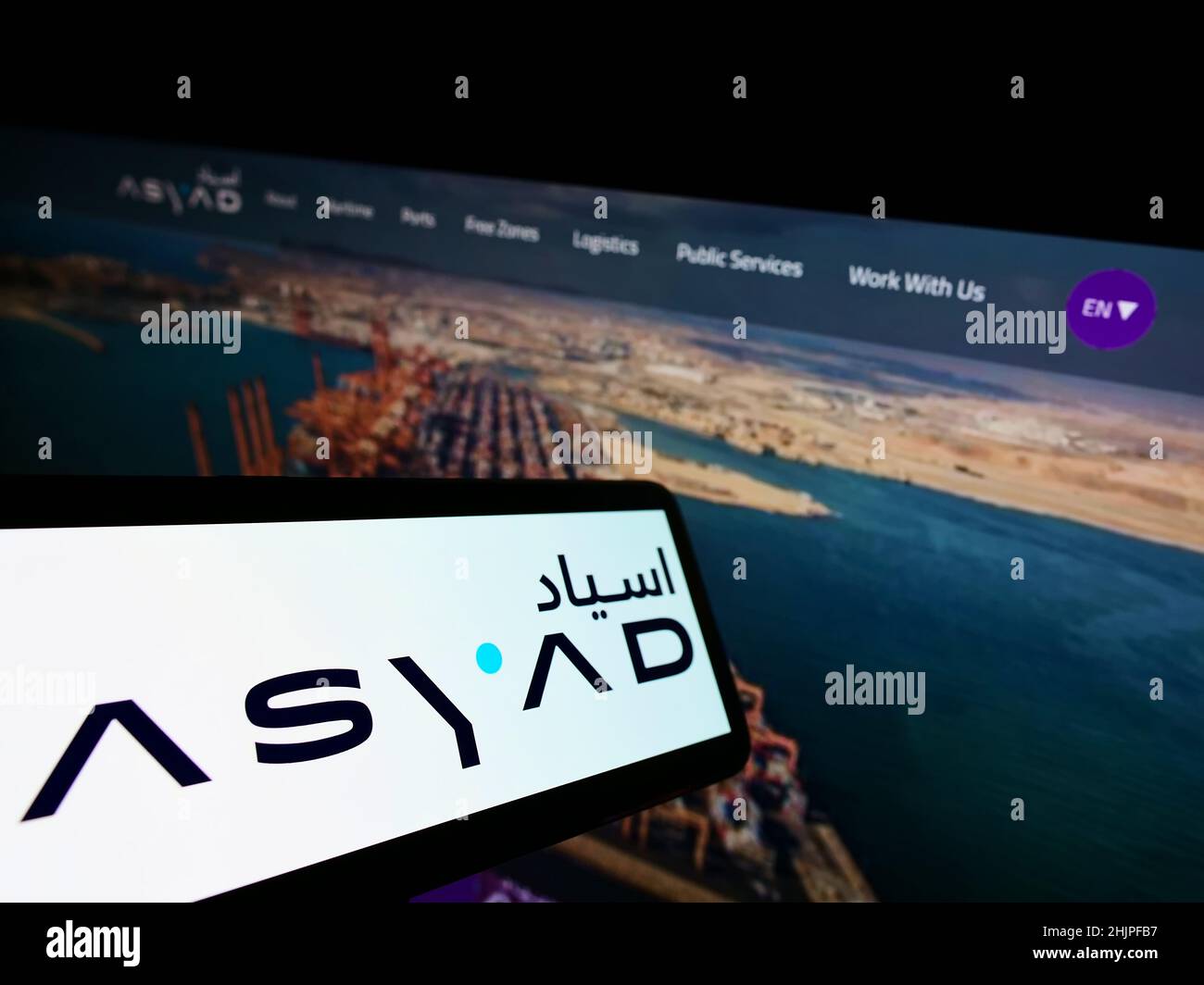 Smartphone con el logotipo de la compañía logística omaní ASYAD Group en pantalla frente al sitio web de negocios. Enfoque en el centro de la pantalla del teléfono. Foto de stock