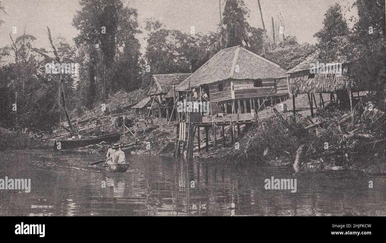 Asentamiento por uno de los ríos finos que son los principales medios de comunicación de Borneo. Malasia (1923) Foto de stock