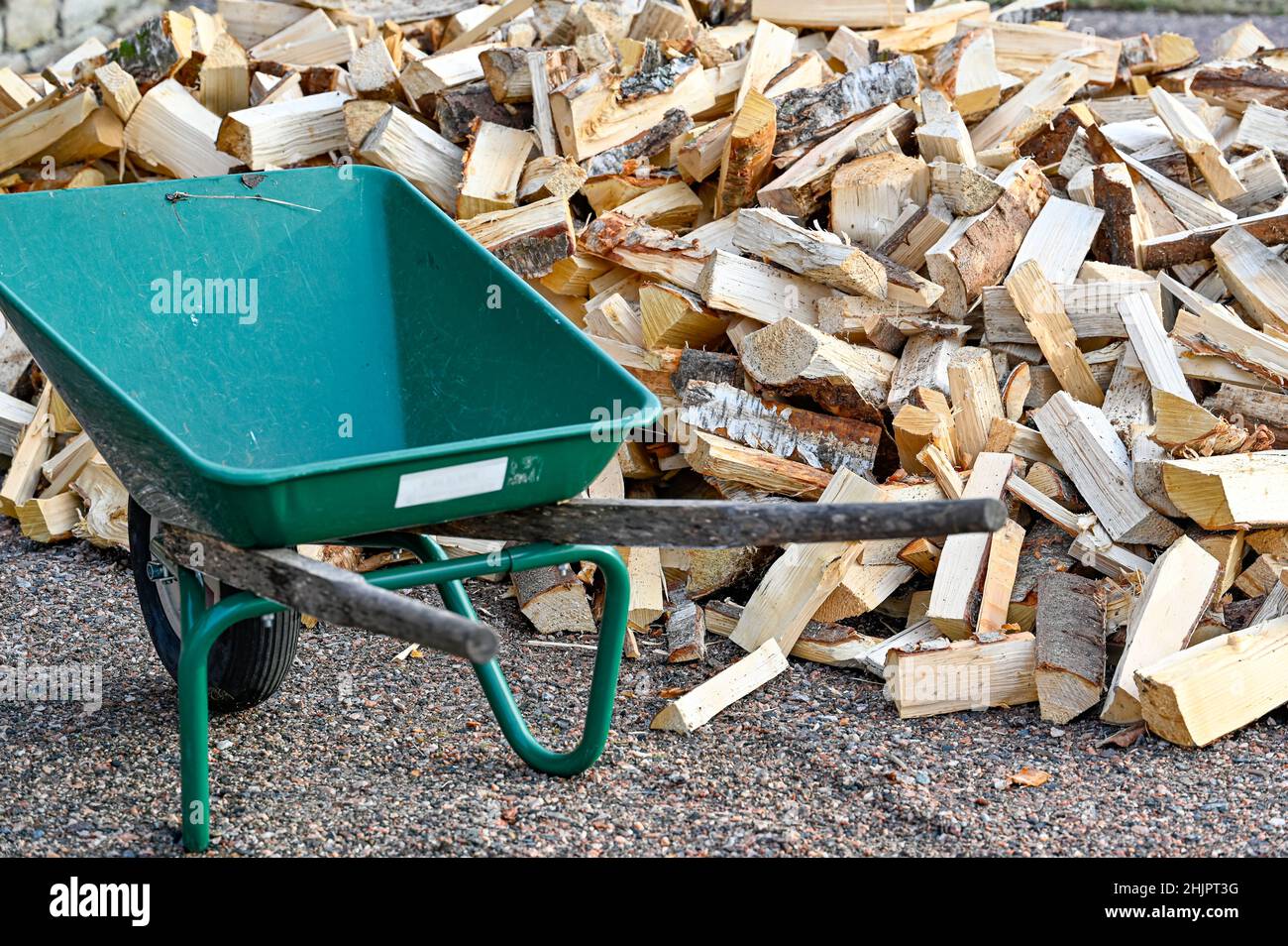 pila de leña y carretilla verde para el transporte Fotografía de stock -  Alamy