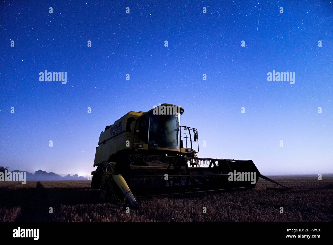 Cosechadora cosechadora por la noche con cielo estrellado  Norfolk Reino Unido Foto de stock