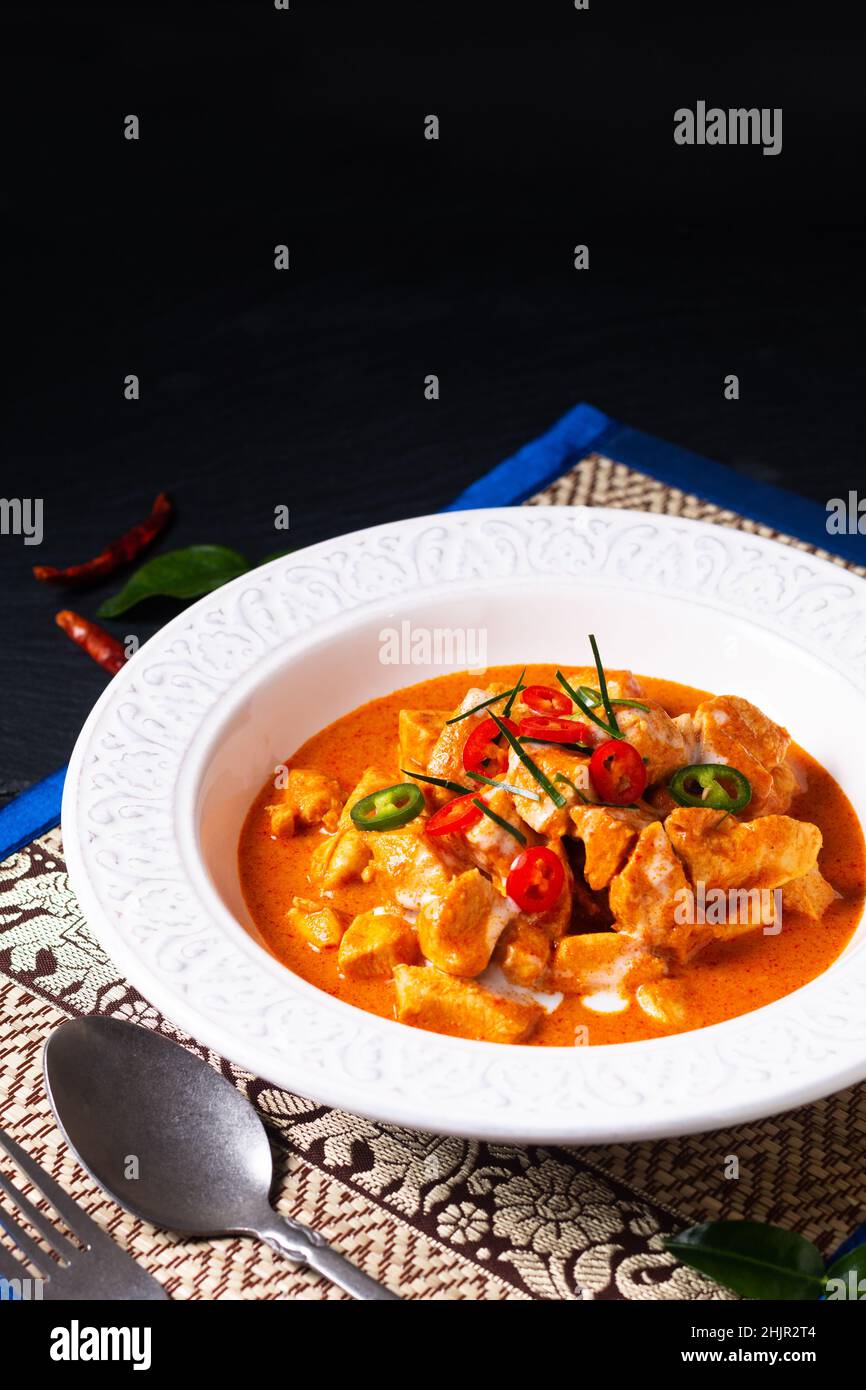 Concepto de comida tailandesa Auténtico pollo tailandés Panang Curry, Panang Kai en un tazón de cerámica sobre fondo negro con espacio de copia Foto de stock