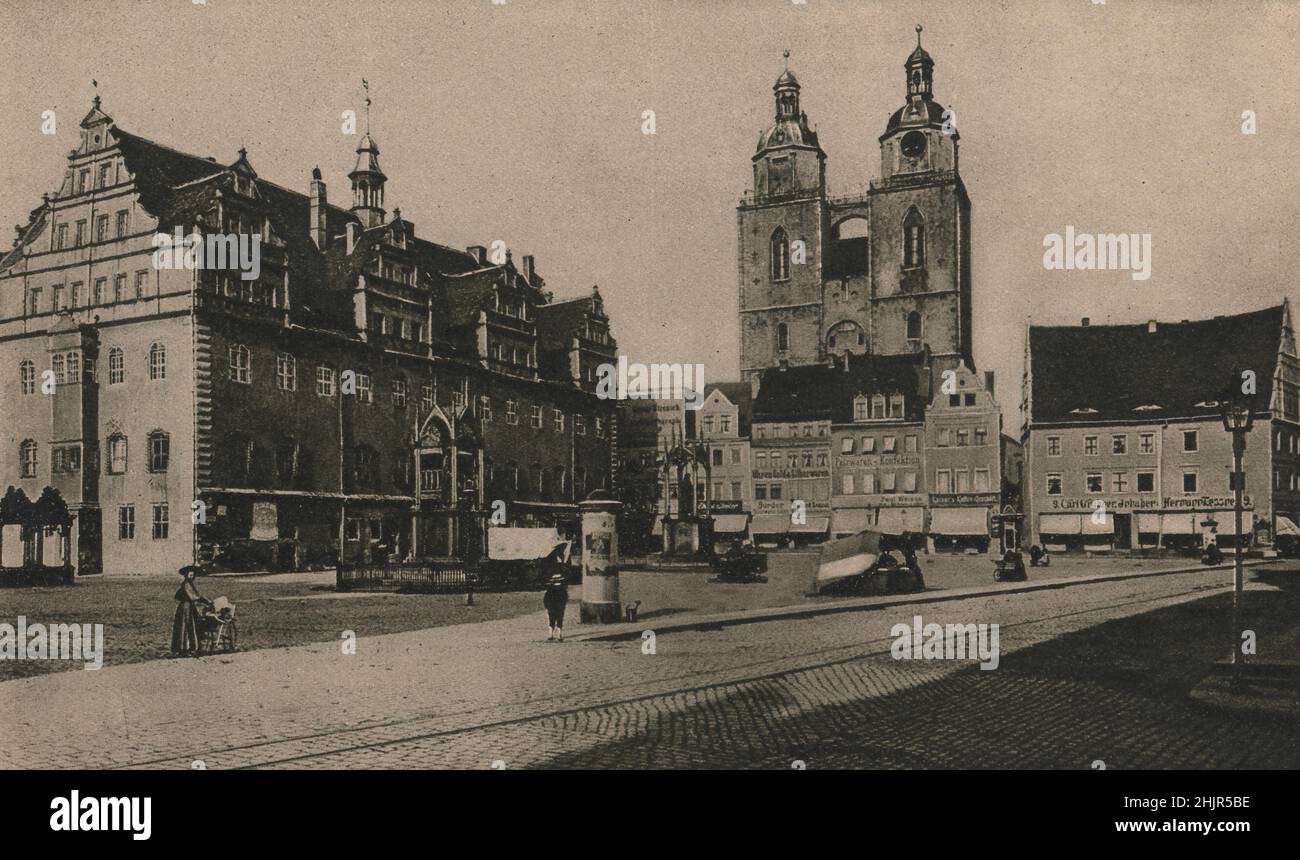 Rathaus en el mercado de Wittenberg canopied estatuas de bronce conmemorar Lutero y Melanchthon. Stadtkirche a la derecha. Alemania (1923) Foto de stock