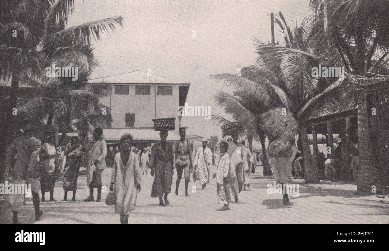 Tipos de población de Zanzíbar vistos en el mercado de la ciudad capital, con sombra de palmeras. Tanzania (1923) Foto de stock