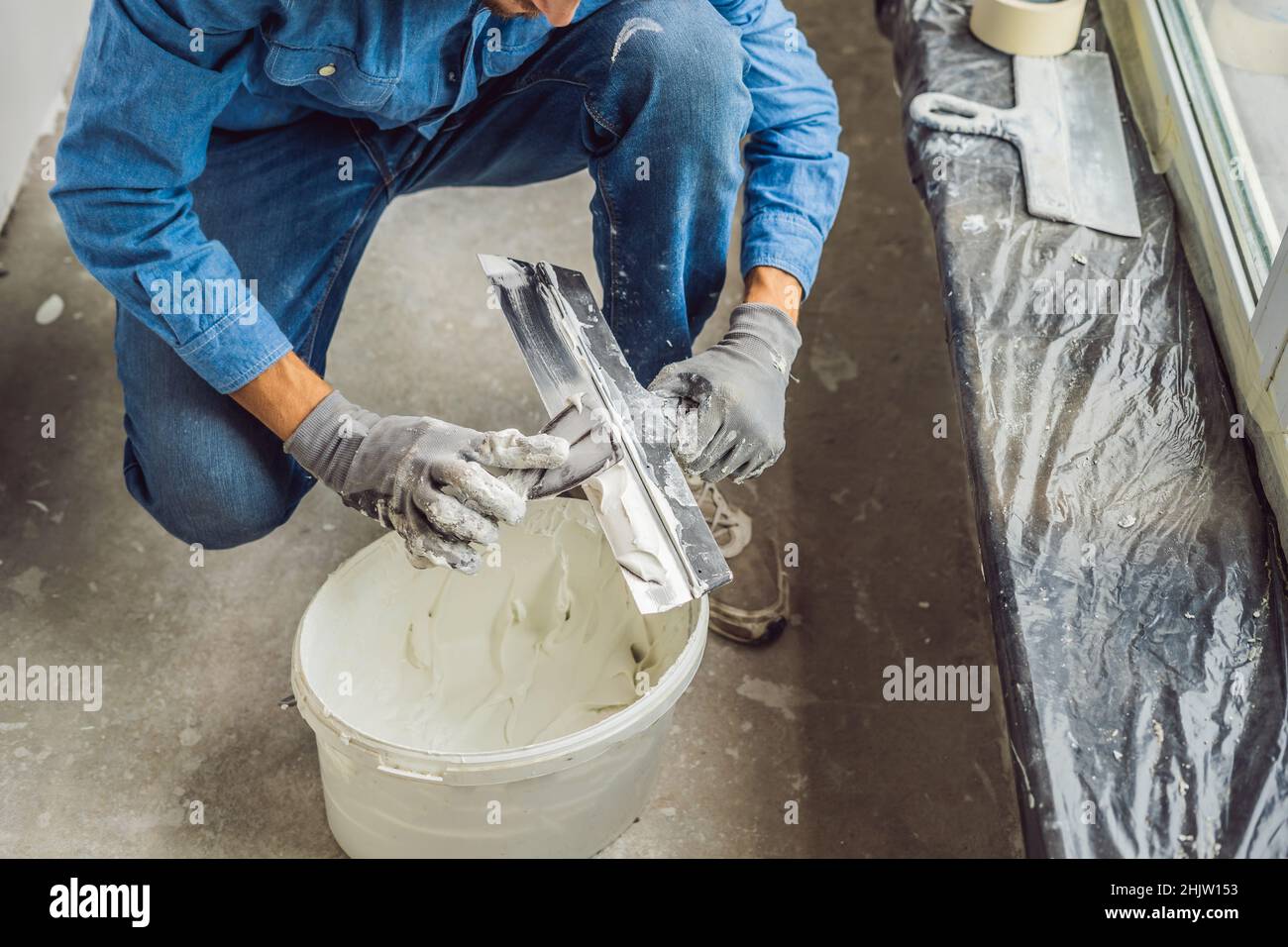 Master está aplicando masilla blanca sobre una pared y manchas por cuchilla  para masilla en una sala de Rehabilitación de casa en el día Fotografía de  stock - Alamy