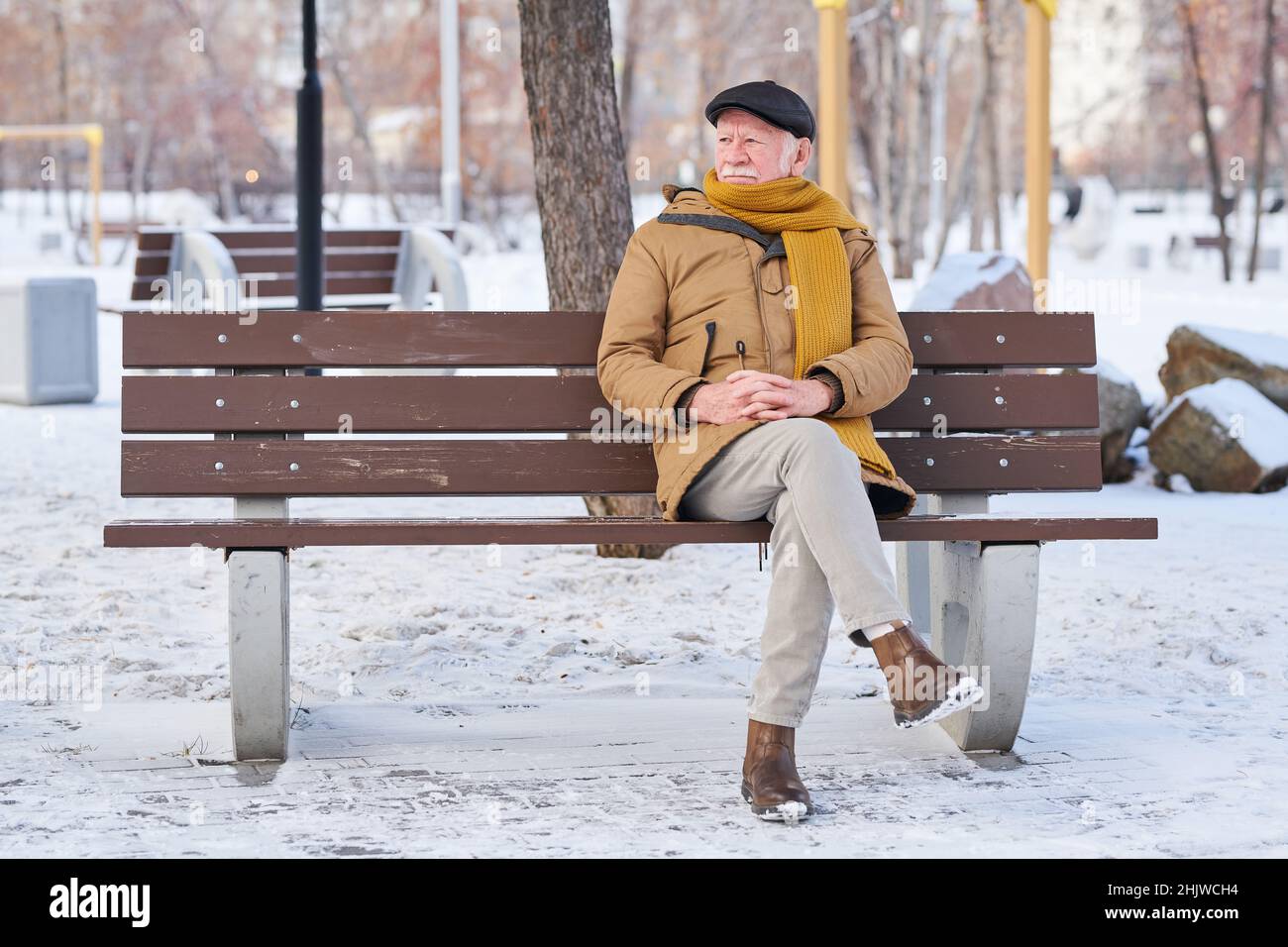 Hombre mayor con ropa de abrigo solo en el banco y mirando con visión pensativa, respira aire fresco en parque Fotografía de stock - Alamy