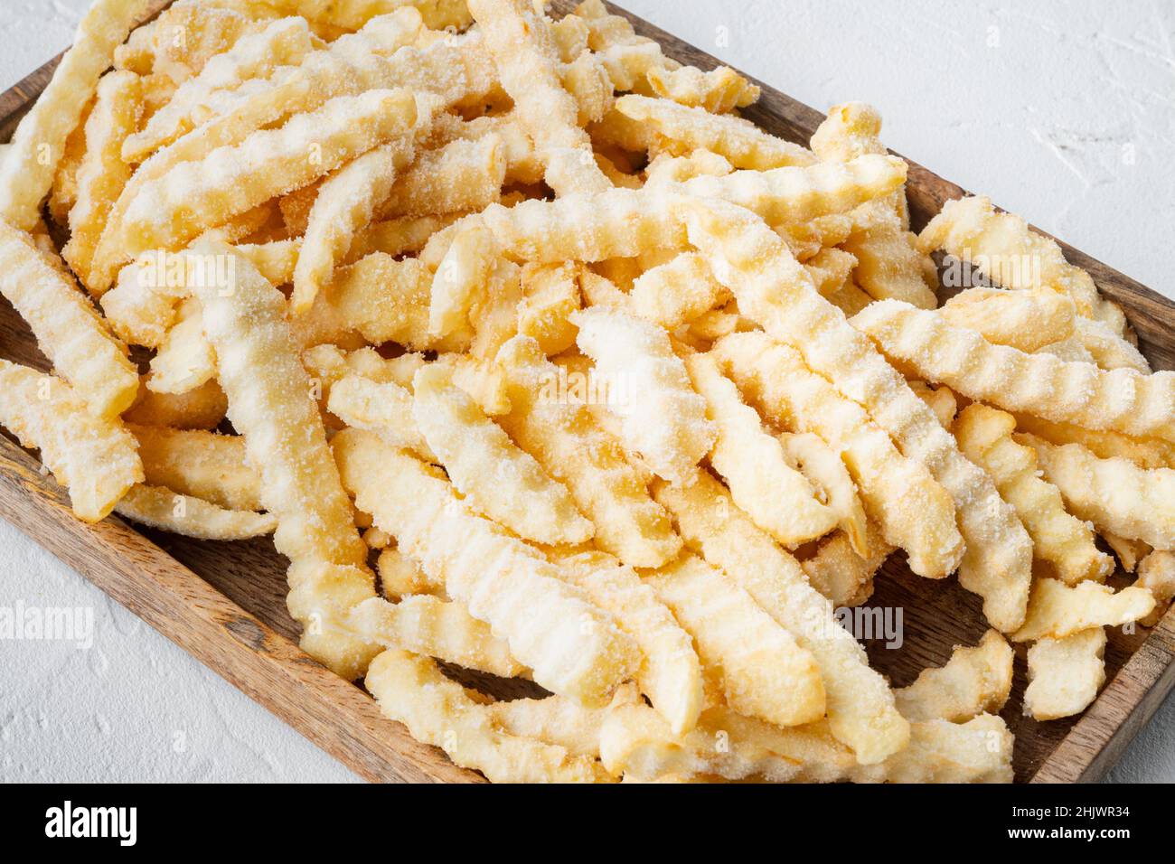 Juego de patatas fritas congeladas en horno, sobre bandeja de madera, sobre  fondo blanco Fotografía de stock - Alamy