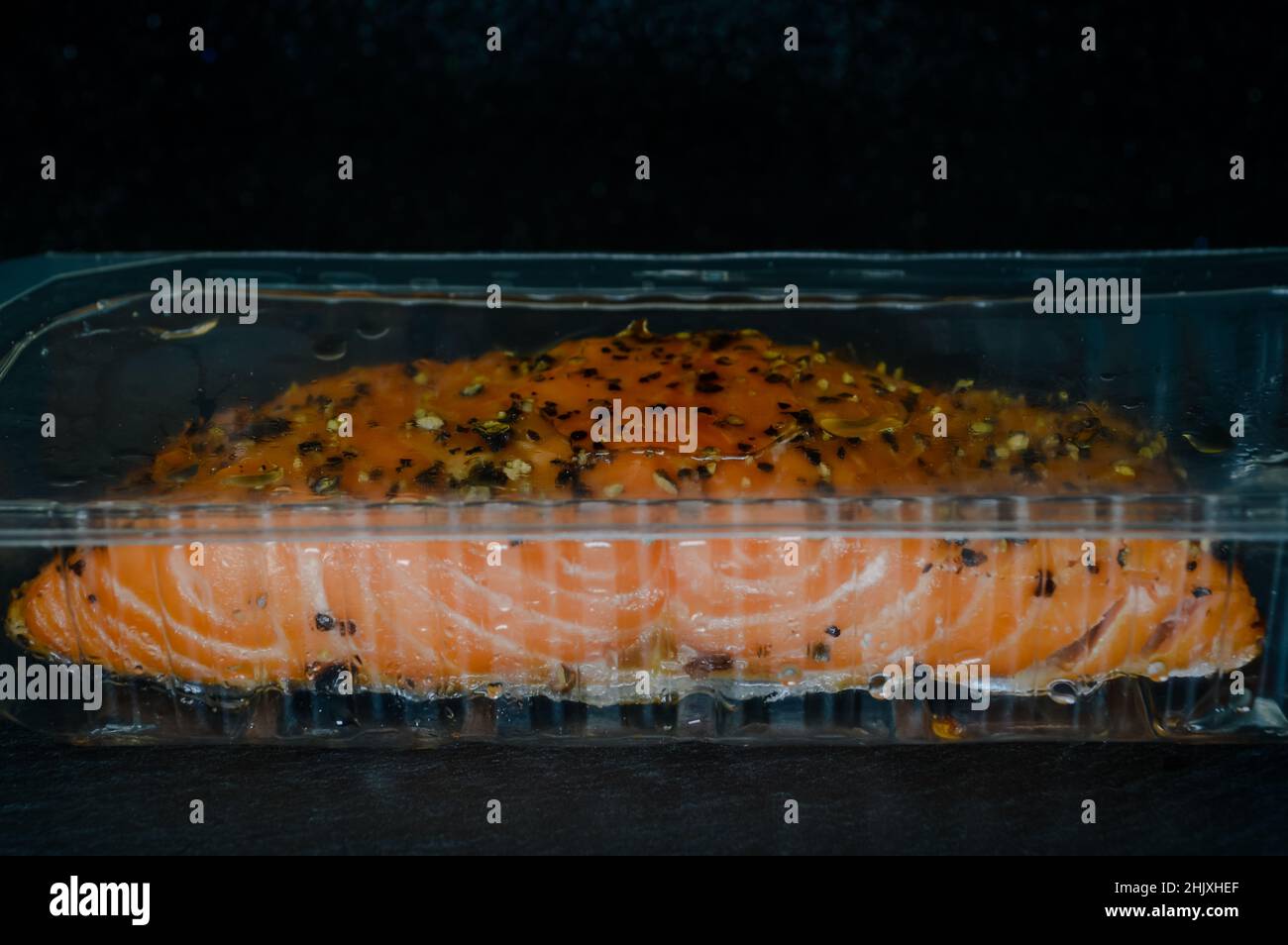 filete de salmón ahumado caliente con sabor a pimienta negra en su embalaje  protector de plástico transparente en una bandeja de pizarra Fotografía de  stock - Alamy