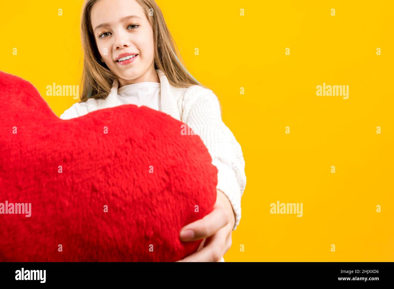 Declaración de amor. Una chica linda sosteniendo un corazón rojo en sus manos. Amor. Día de San Valentín. Felicidades por las vacaciones. Foto de stock