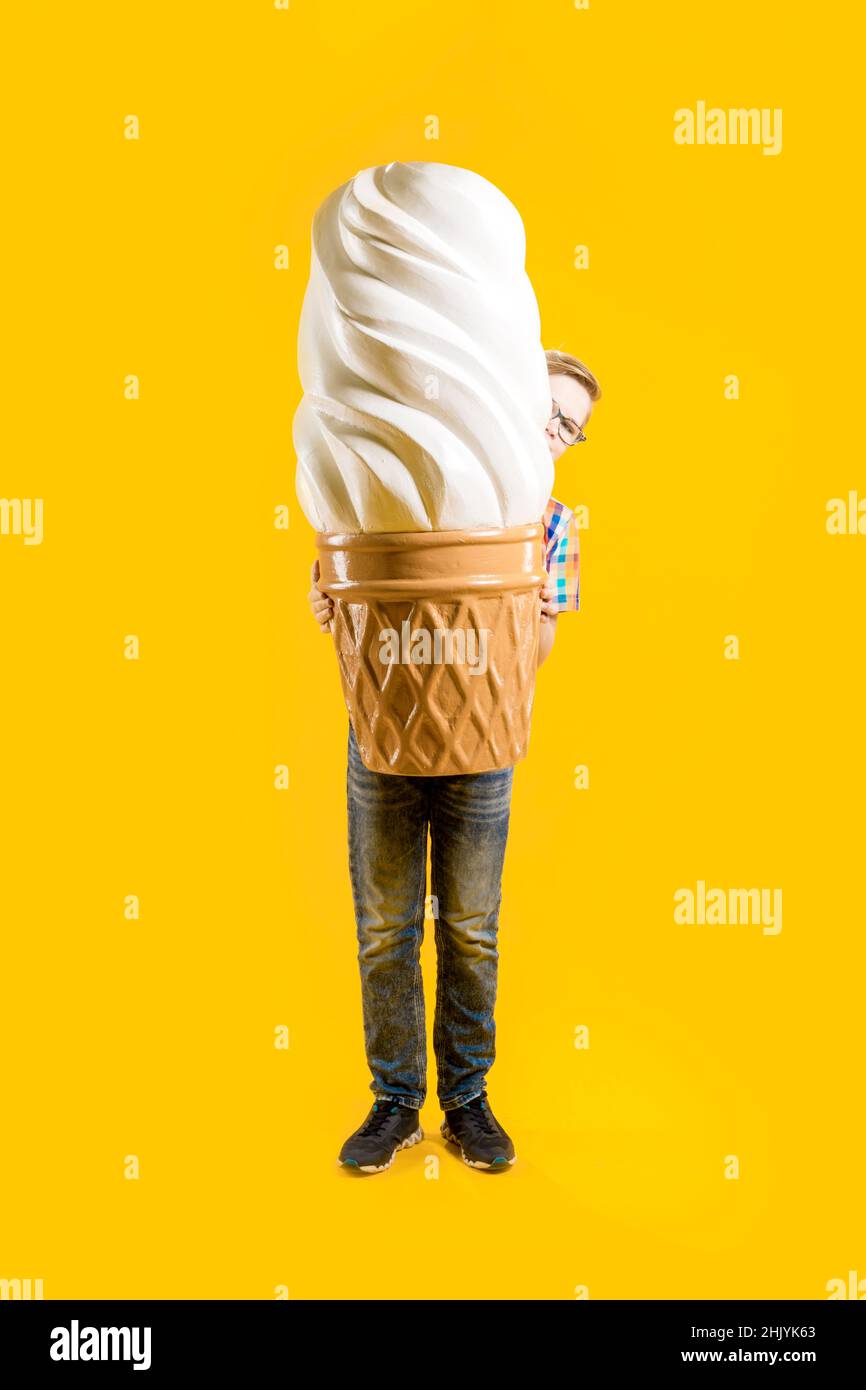 Delicioso postre. Un niño lindo está sosteniendo un helado enorme en un cono de gofre. Adolescente alegre. Confitería. Foto de stock