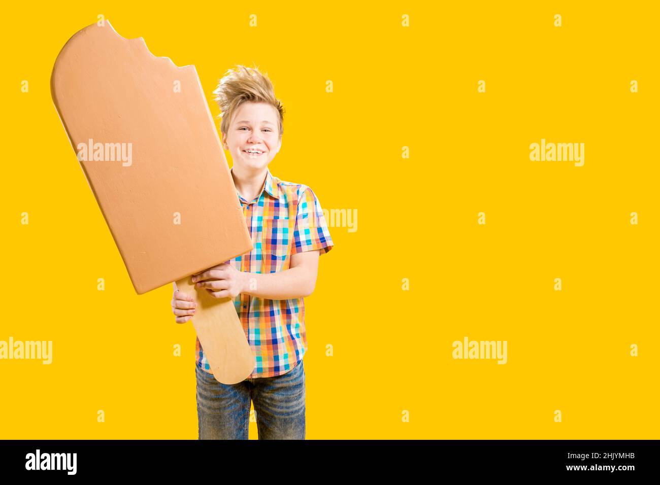 Delicioso postre. Adolescente alegre. Pastelería. Un chico lindo sostiene un helado enorme en un palo en sus manos. Foto de stock