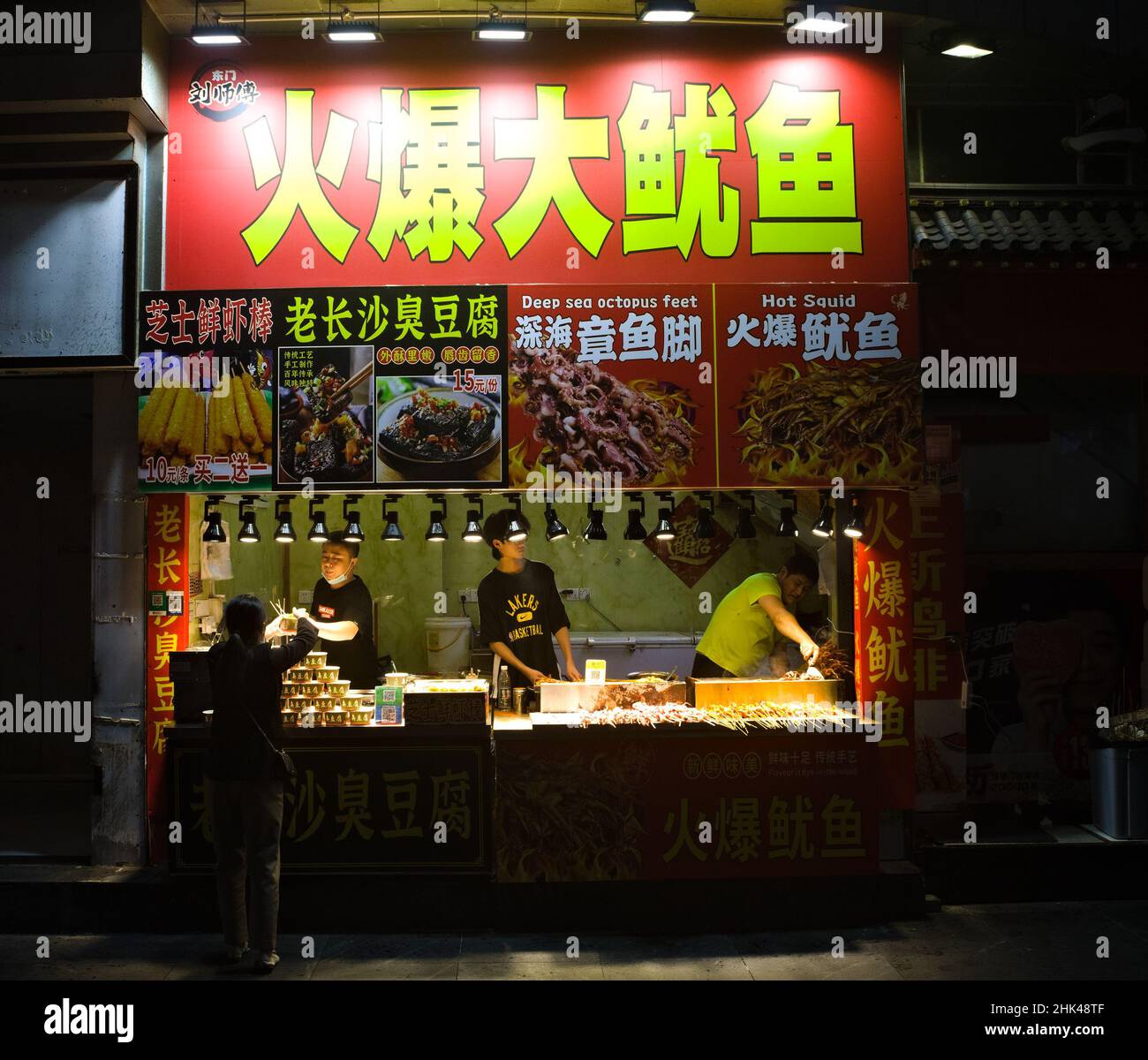 Puesto de comida china que vende bocadillos de calamar a un cliente en Shenzhen, China Foto de stock