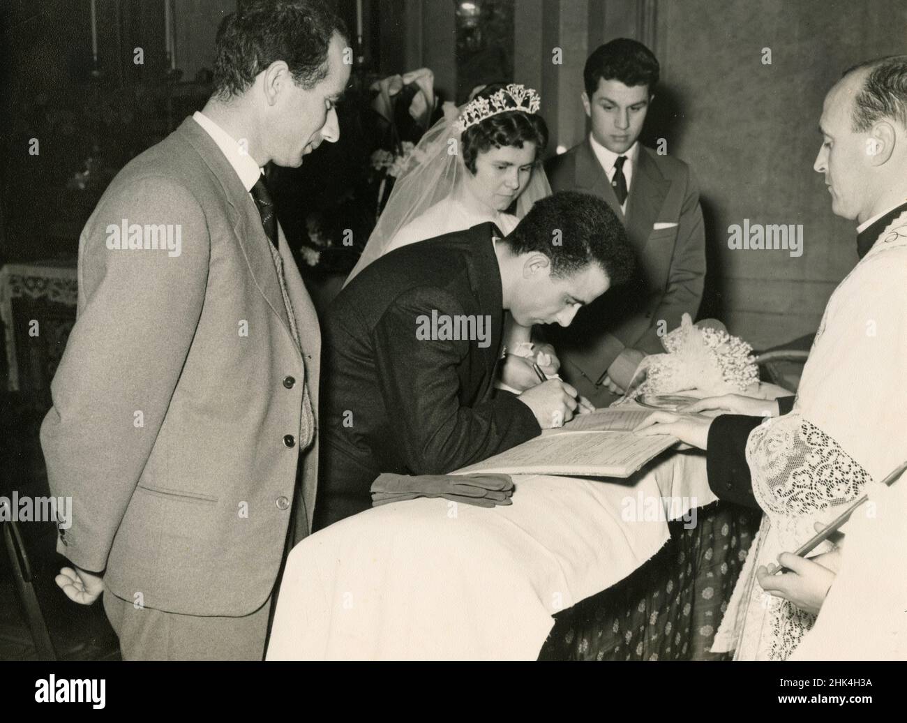 Boda en Italia durante el 1950s: La novia y el novio firmando los papeles en la iglesia Foto de stock