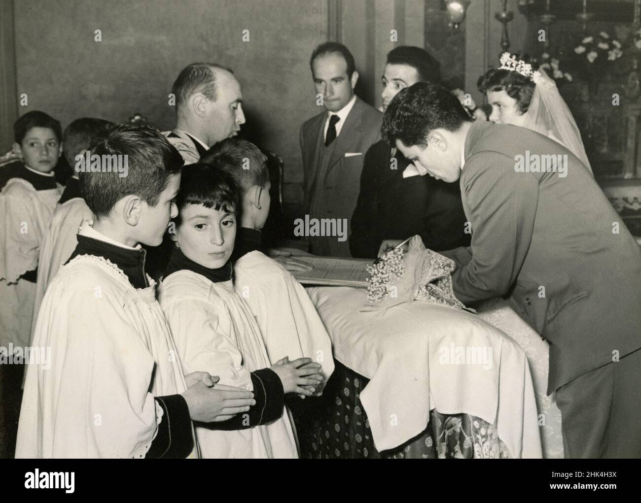 Boda en Italia durante el 1950s: La novia y el novio firmando los papeles en la iglesia Foto de stock