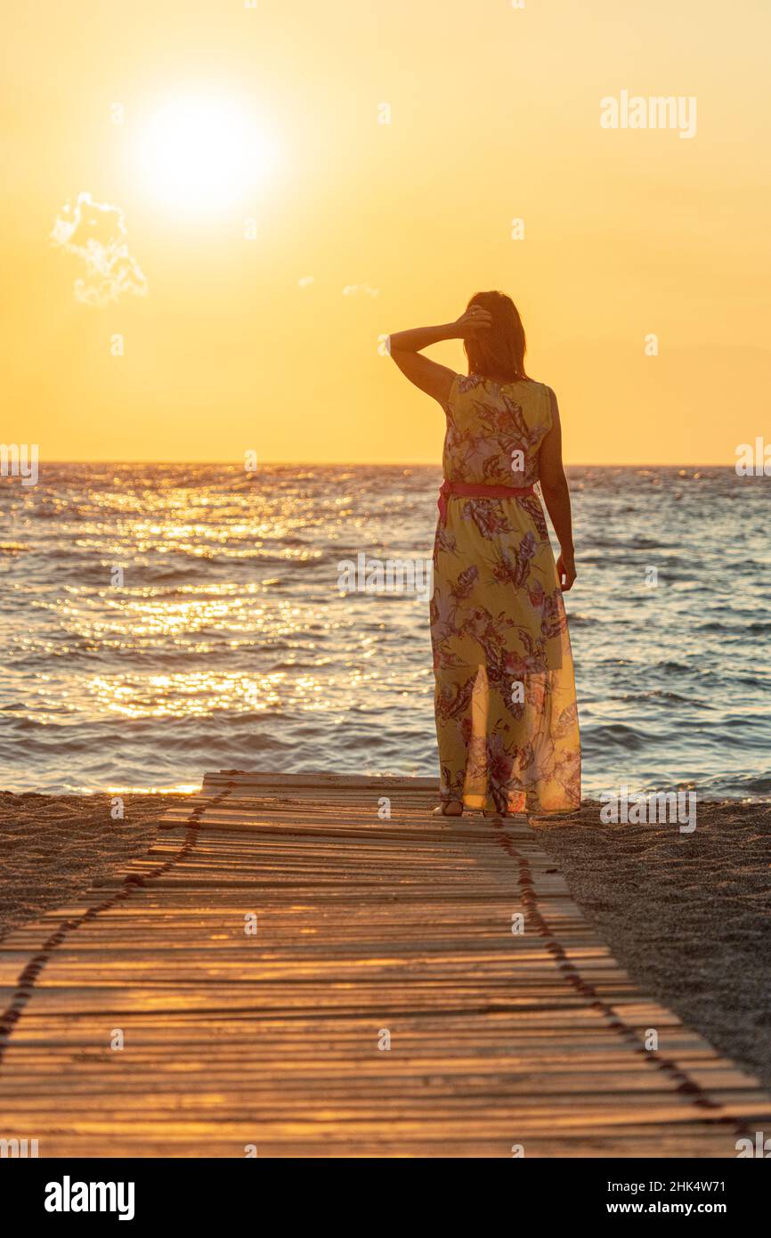 Encantadora mujer contemplando el mar al atardecer en la playa de Matala, Creta, Islas griegas, Grecia, Europa Foto de stock