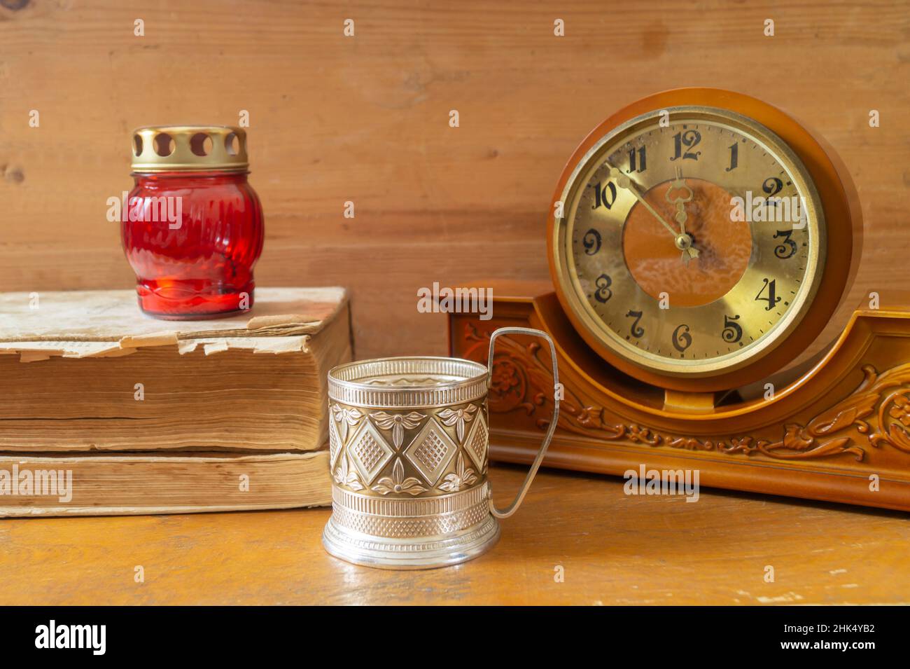 Un viejo reloj de madera en un estante con libros. Primeros planos de los objetos de inicio Foto de stock