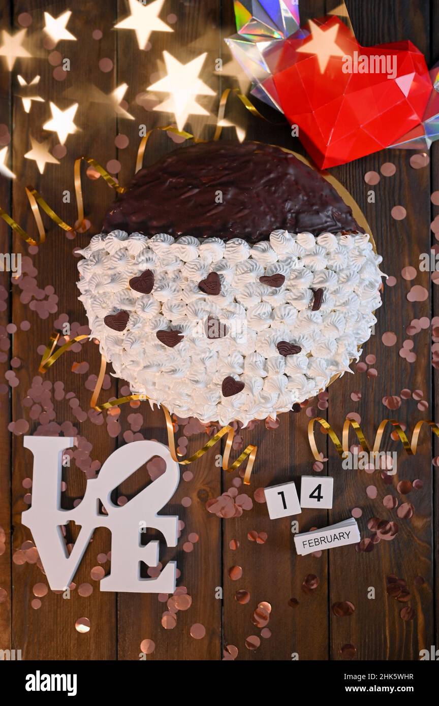 Pastel con crema y chocolate para el día de San Valentín. Febrero 14 calendario y corazón. Con luces y estrellas. Foto de stock