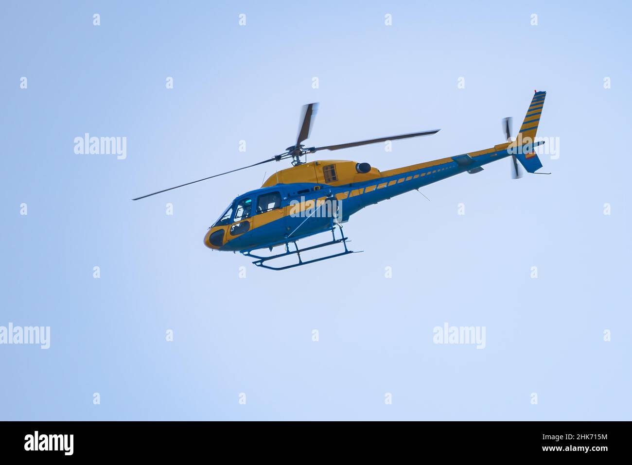 Helicóptero amarillo y azul de vigilancia de tráfico patrullando las carreteras y autopistas para controlar la conducción imprudente. Foto de stock