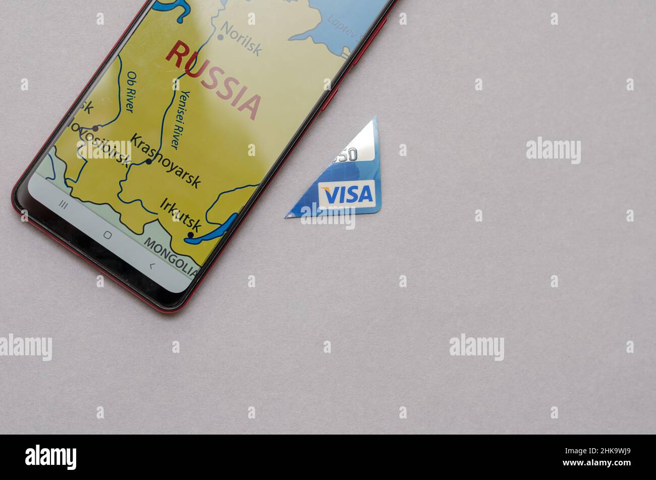 Smartphone y tarjeta Visa Bank Piece sobre un fondo gris. Hay un mapa de  Rusia en la pantalla del smartphone. Una pieza cortada de tarjeta de  crédito azul Fotografía de stock -