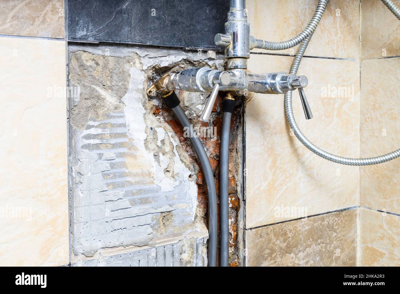 nuevas tuberías de agua de polietileno de alta densidad conectadas al grifo  de la ducha dentro de la pared de ladrillo roto con azulejos de cerámica de  la pared removidos en casa