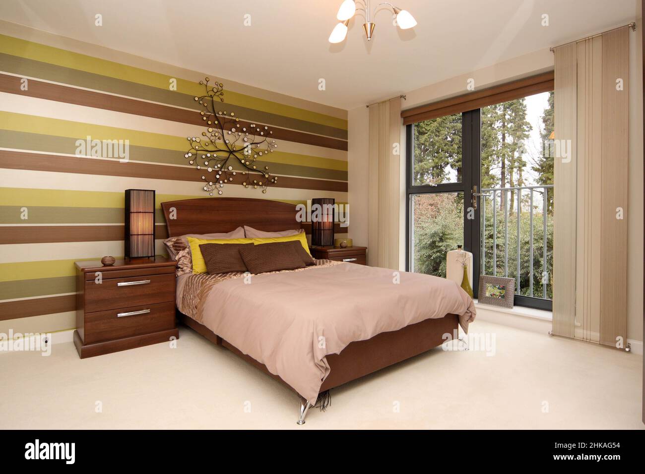 Dormitorio con pared de características en color marrón verde amarillo, balcón juliette, vista al exterior, Foto de stock