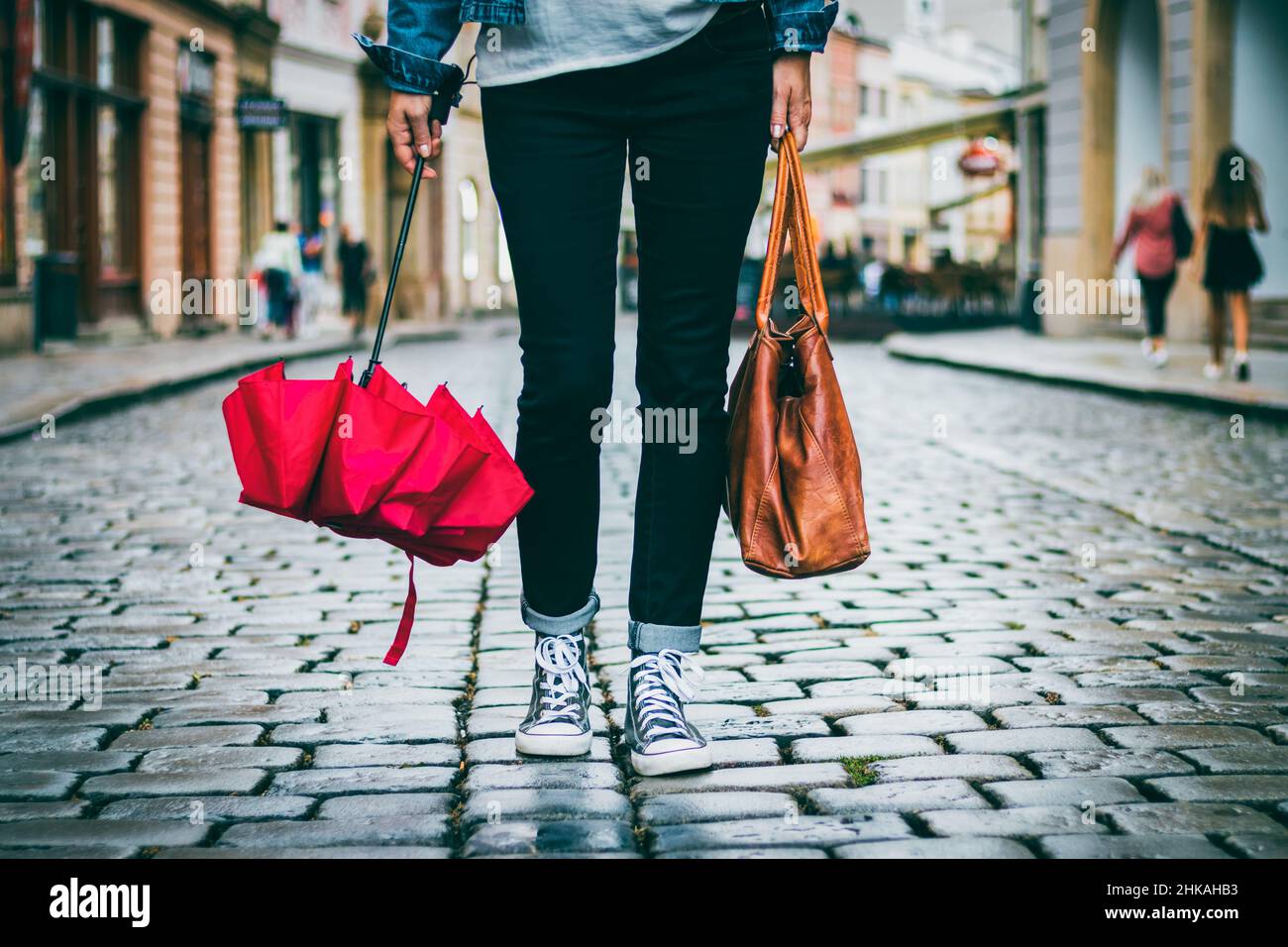 Tumba Exquisito antecedentes Mujer sosteniendo bolsa de cuero y paraguas rojo y ella camina en la calle  después de la lluvia. Concepto de moda en la ciudad. Mujer de moda con ropa  informal Fotografía de