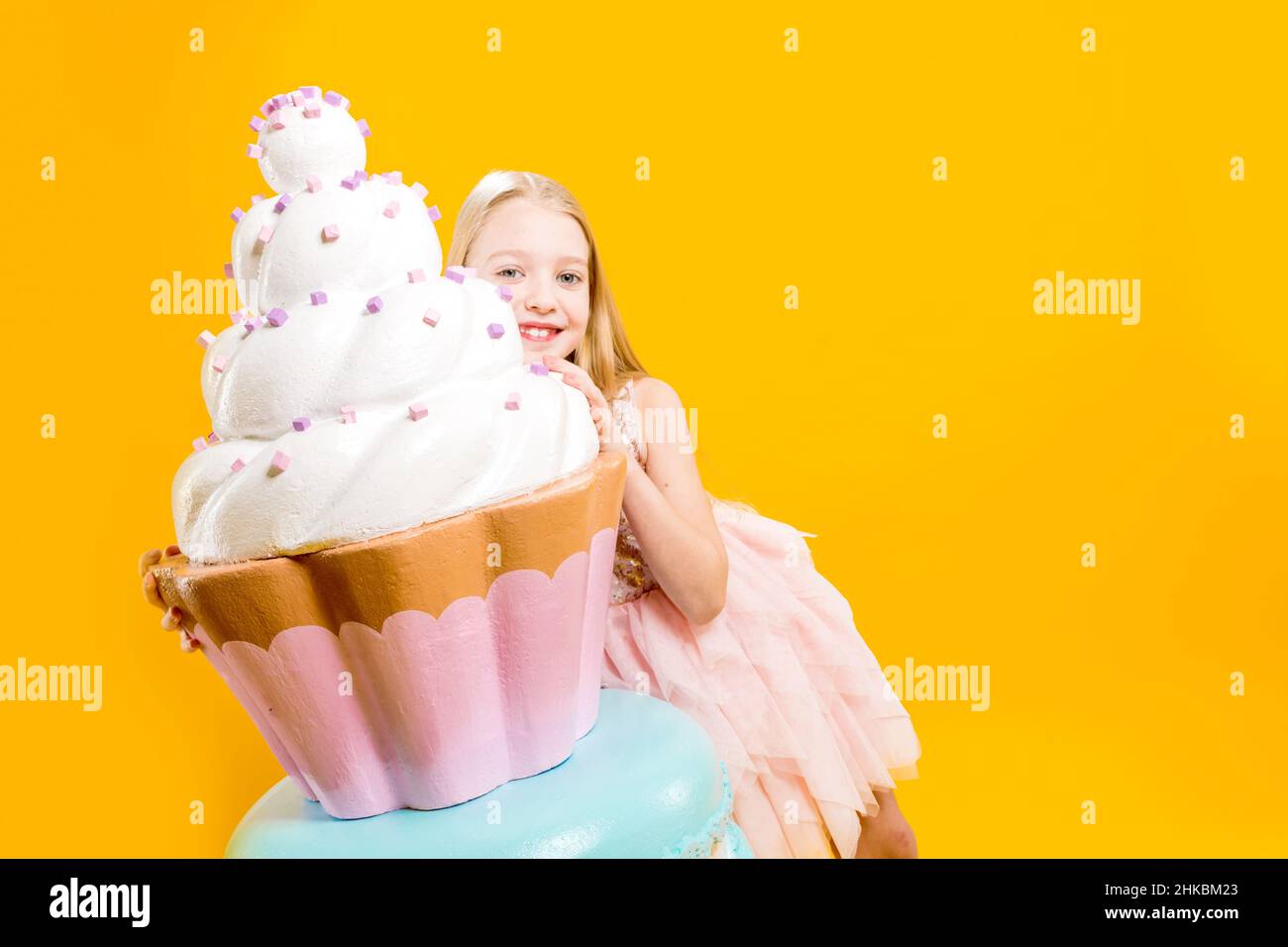 Delicioso postre. La chica está sosteniendo un enorme cupcake cubierto de crema. Dulzura. Pastelería. Foto de stock