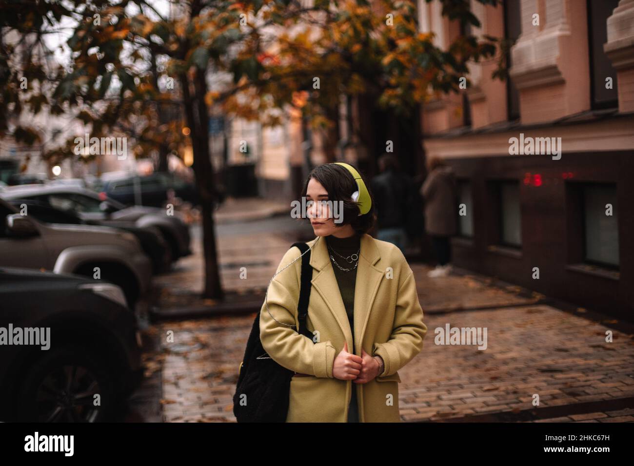 Una mujer joven atenta escuchando música en los auriculares caminando por la calle Foto de stock