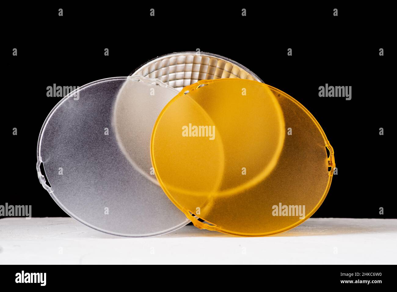 Reflector estándar con difusor blanco mate y amarillo sobre fondo negro. Diferentes difusores para temperaturas de luz. Accesorio para flash de estudio Foto de stock
