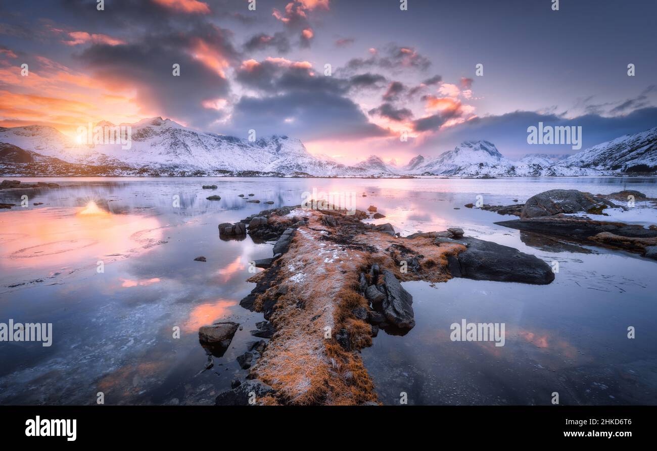 Costa del mar, montañas nevadas y cielo azul con nubes rosadas Foto de stock