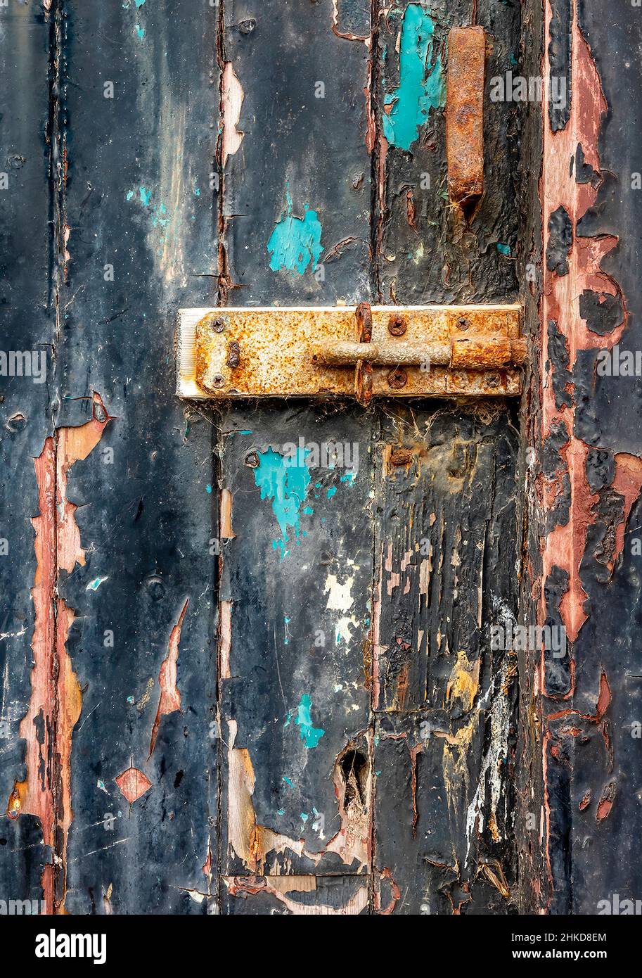 parte de una puerta de madera vieja con pintura descascarada y perno oxidado. Foto de stock