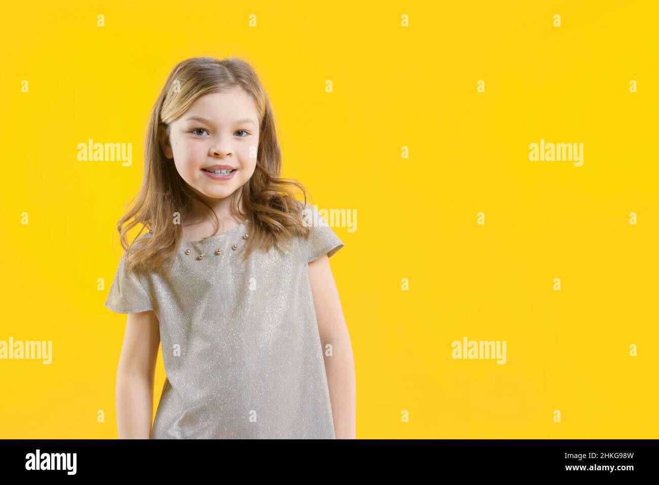 La colegiala está feliz. Retrato de una linda adolescente en una camiseta sobre un fondo amarillo con una sonrisa en su cara. Espacio de copia Foto de stock