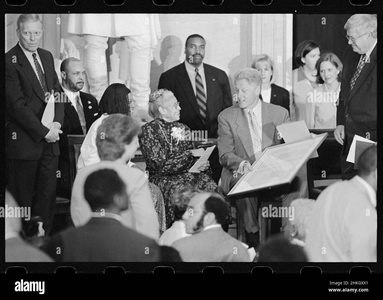 Rosa Parks (1913-2005) En su ceremonia de la Medalla de Oro del Congreso, sentada con la asistente Elaine Steele (izquierda) y el presidente William J Clinton, los representantes Dennis Hastert, Dick Gephardt y otros están detrás de ellos, Washington, DC, 6/15/1999. Foto de stock