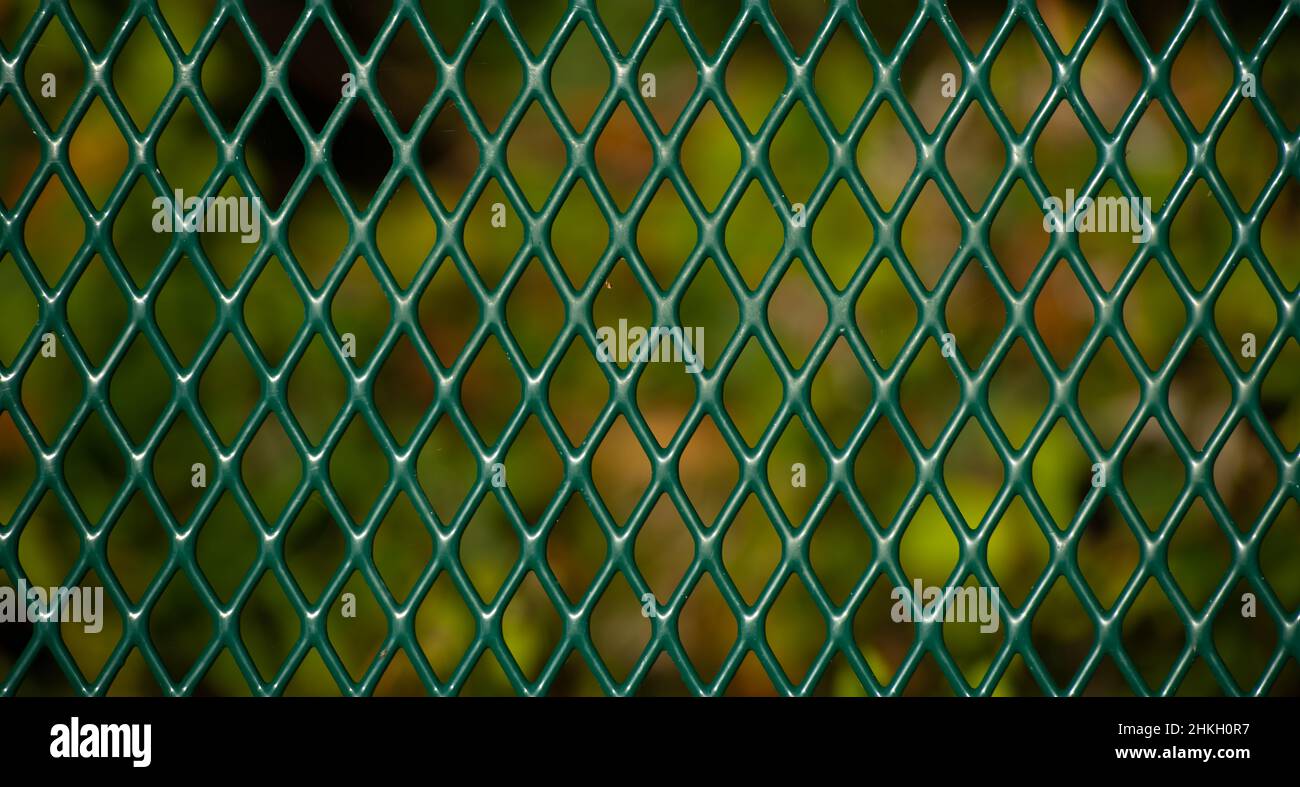 cercado de chainlink verde cerca de una serie de formas de diamante conectado fuerte cercado de metal verde con fondo verde oscuro caída horizontal formato Foto de stock