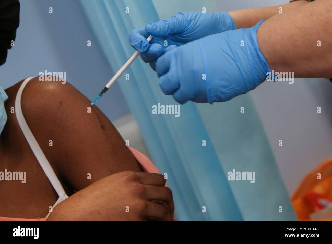 Una vacunadora del NHS administra el booster jab Covid-19 de Pfizer a la mujer, en un centro de vacunación. Foto de stock