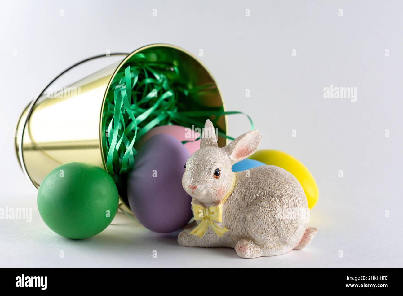 Conejito de Pascua con una pail de huevos de Pascua sobre fondo blanco con espacio de copia. Foto de stock