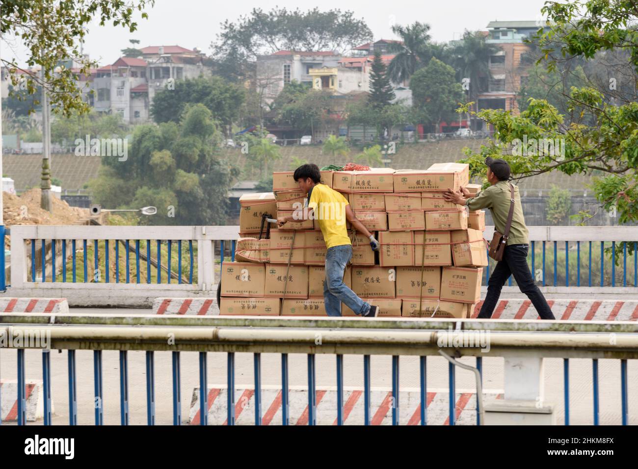 Un comerciante vietnamita empuja una bicicleta cargada de mercancías al otro lado de la frontera desde Hekou, provincia de Yunnan, China, hasta Lao Cai, Vietnam del Norte Foto de stock