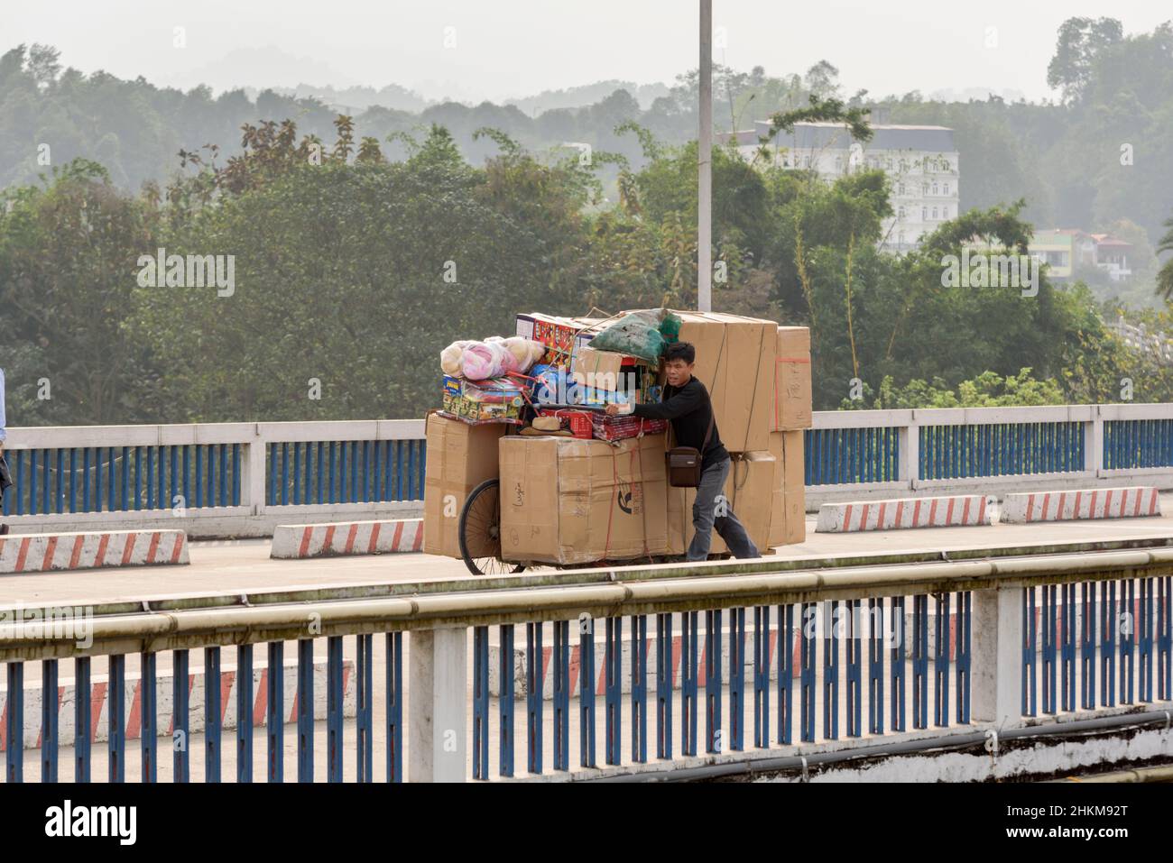 Un comerciante vietnamita empuja una bicicleta cargada de mercancías al otro lado de la frontera desde Hekou, provincia de Yunnan, China, hasta Lao Cai, Vietnam del Norte Foto de stock