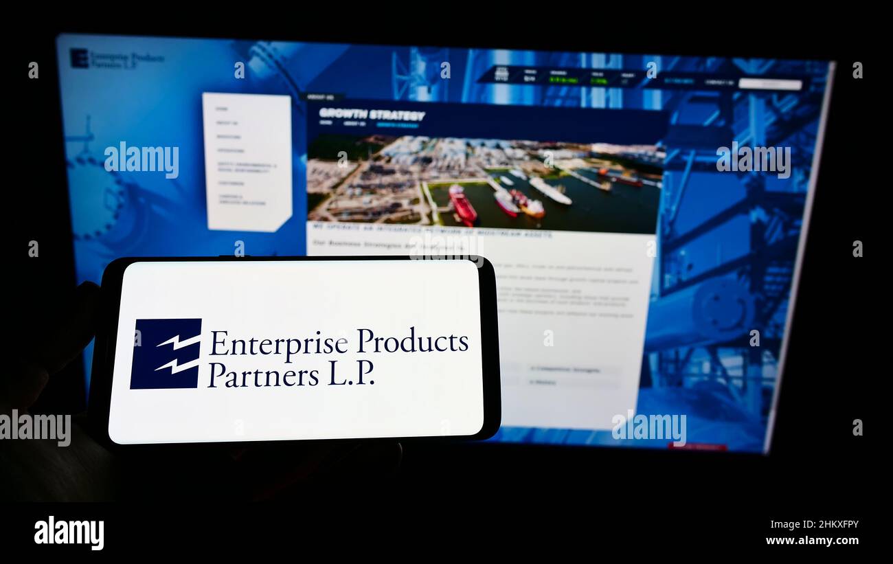 Persona que sostiene el teléfono móvil con el logotipo de la empresa de  pipeline Enterprise Products Partners LP en la pantalla delante de la  página web. Enfoque en la pantalla del teléfono